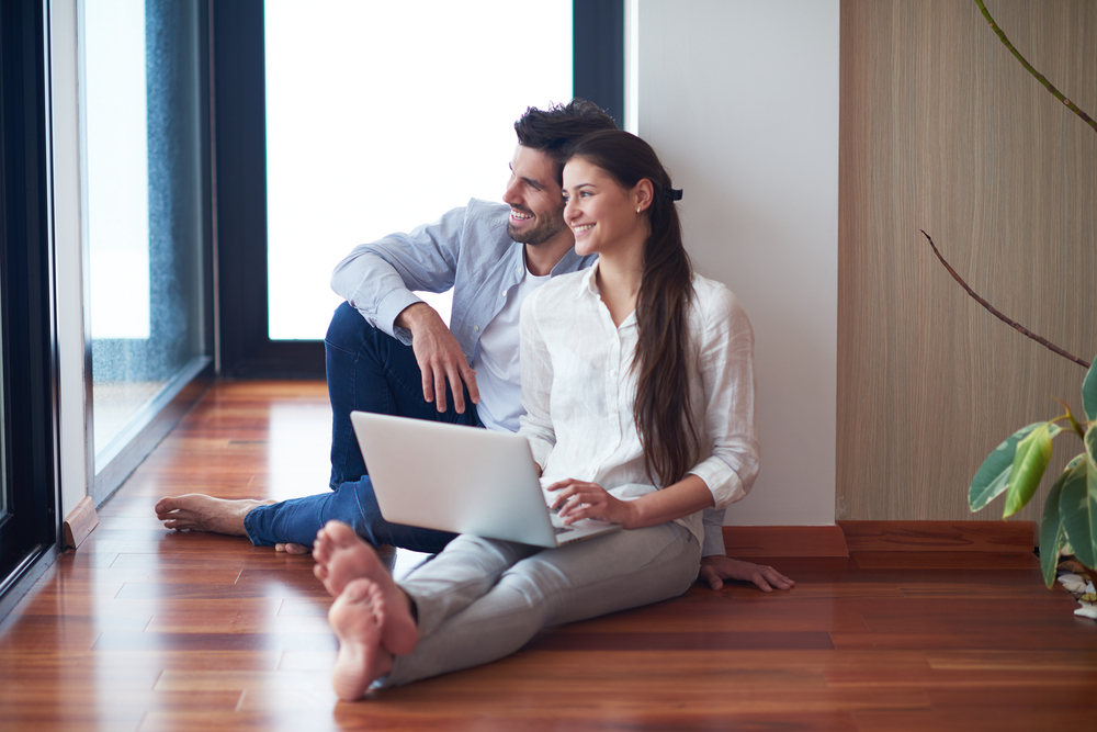 happy young relaxed  couple working on laptop computer at modern home interior